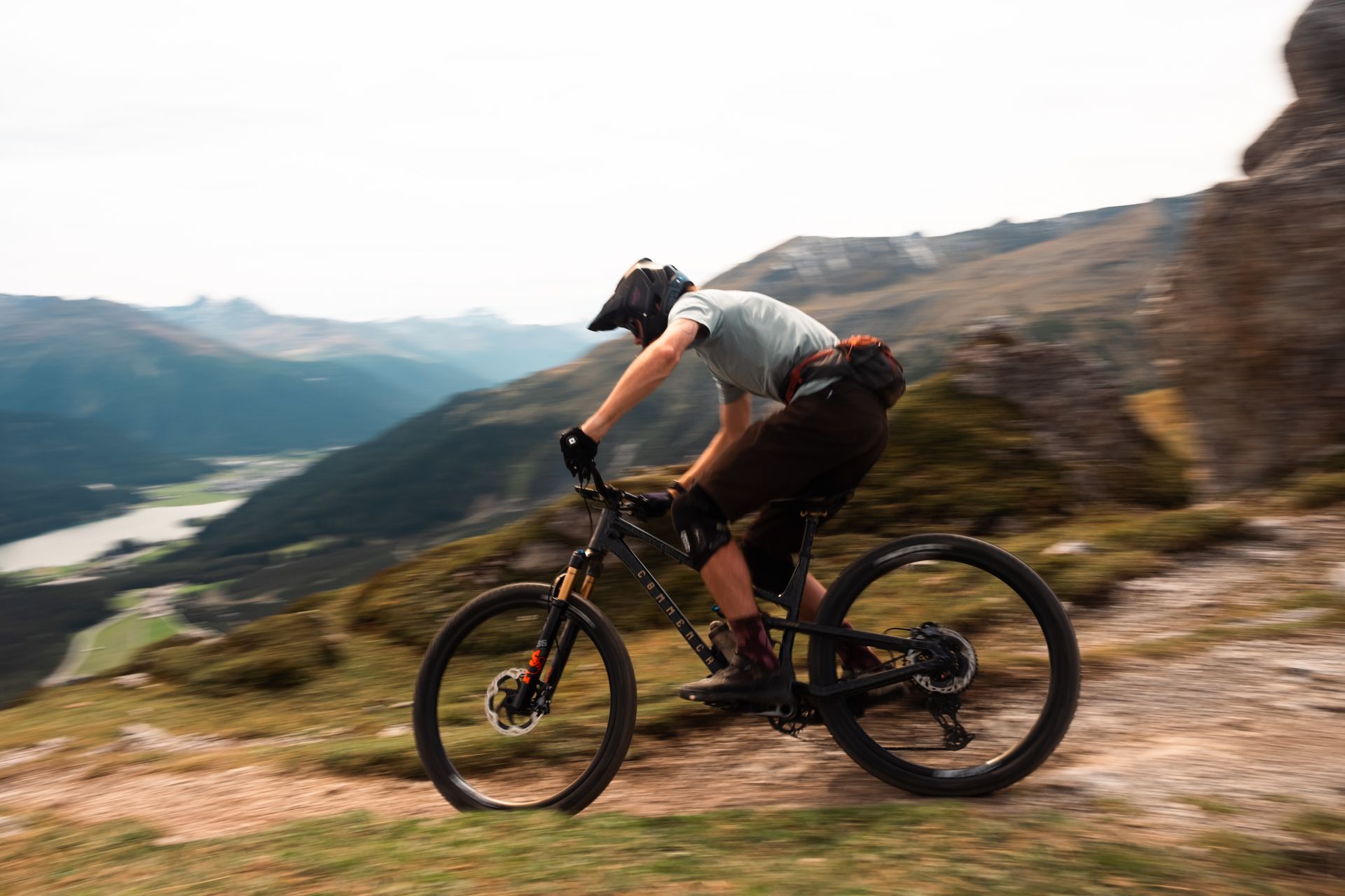 Rider on a ridge trail above a valley lake